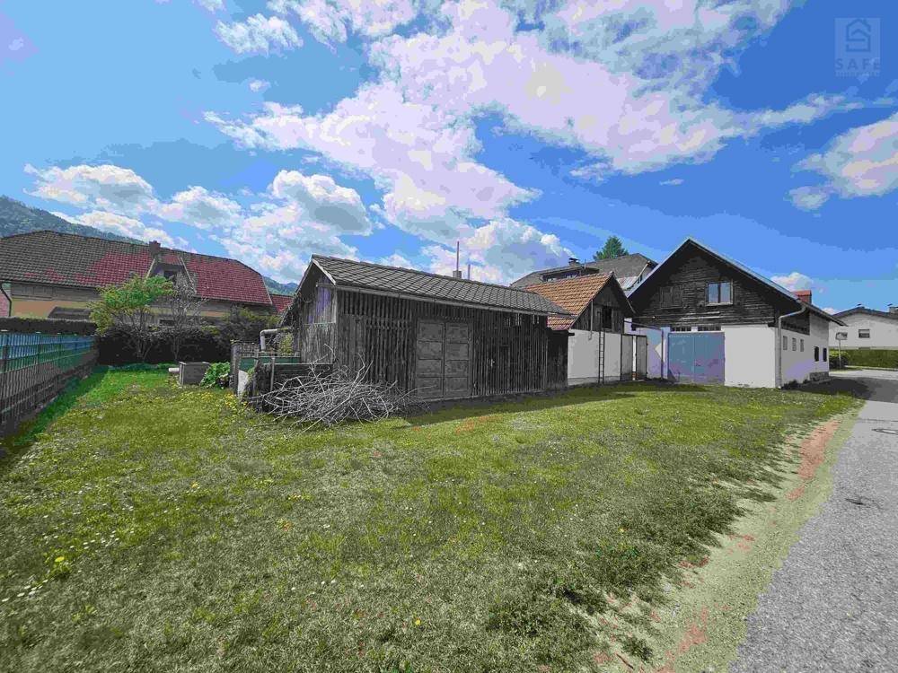 Altes Holzschuppen und weitere Nebengebäude auf einem Grundstück mit Rasenfläche.