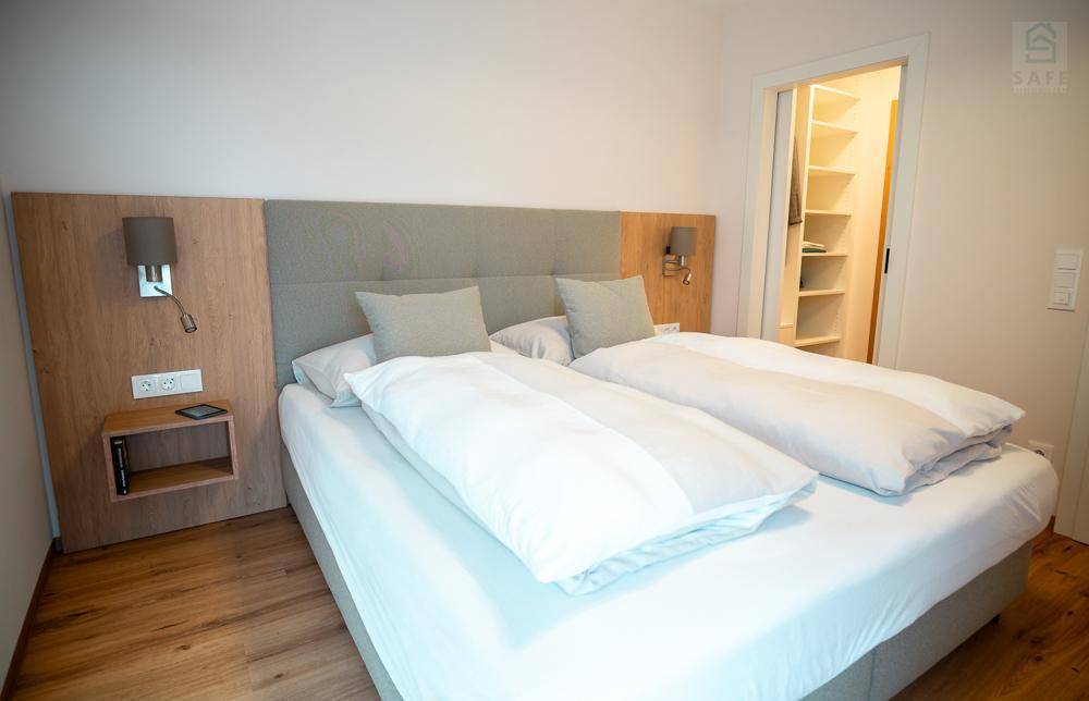 Schlafzimmer mit Doppelbett und direktem Zugang zu einem begehbaren Kleiderschrank mit viel Stauraum.