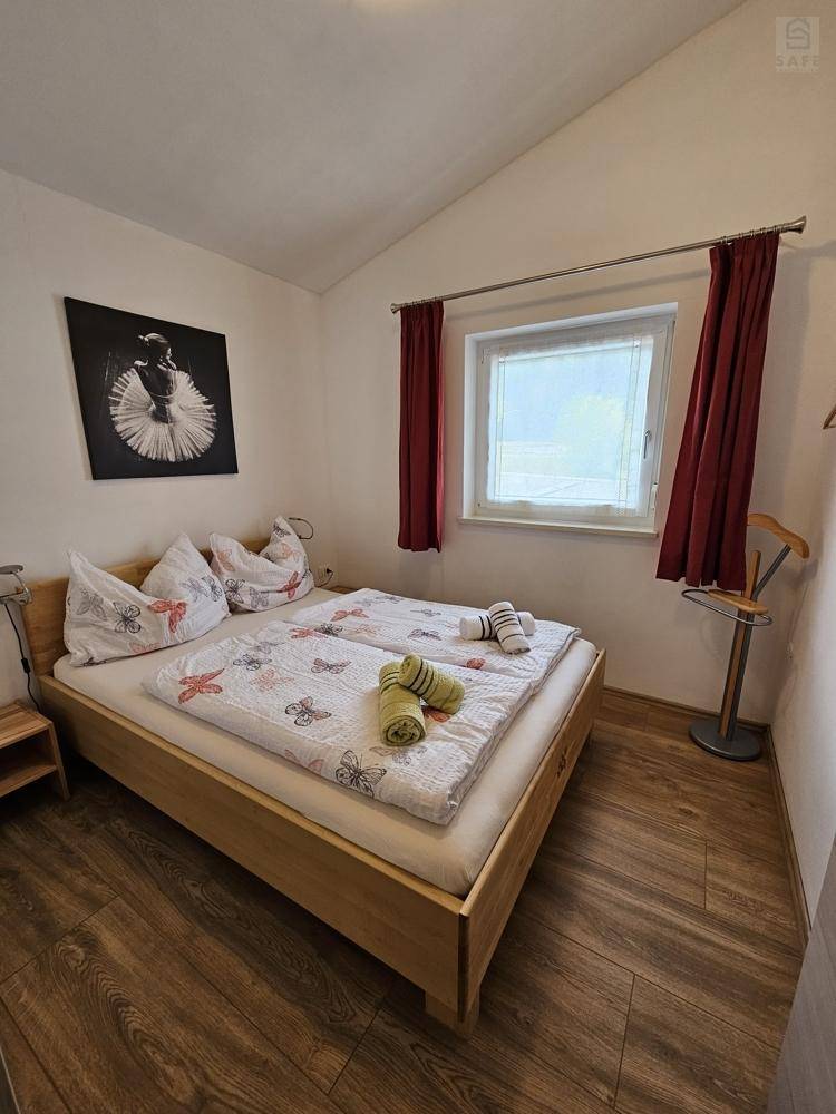 Helles Schlafzimmer mit Doppelbett, Holzboden und schrägen Decken.