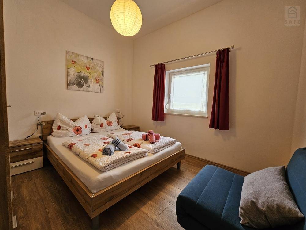 Gemütliches Schlafzimmer mit Doppelbett, Holzboden und einem kleinen Sofa.