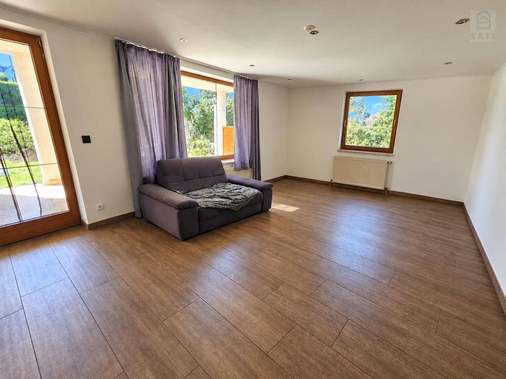 Helles Wohnzimmer mit Holzboden, einem Sofa und Zugang zur Terrasse oder Balkon.