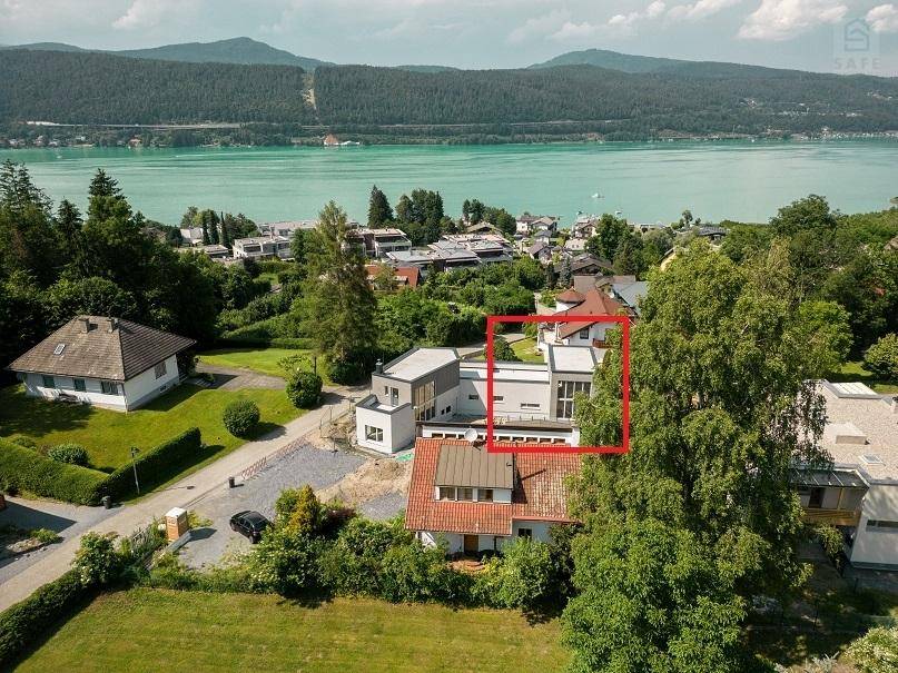Luftaufnahme der Immobilie und der Umgebung mit See im Hintergrund, das Gebäude ist markiert.