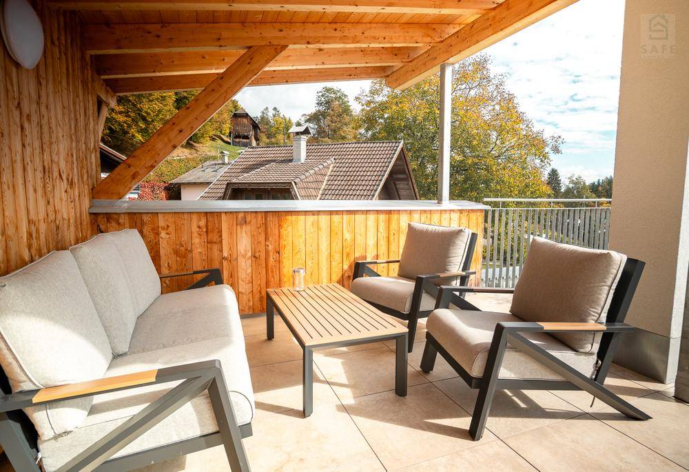 Gemütlicher überdachter Balkon mit Holzverkleidung und bequemen Outdoor-Möbeln, ideal zum Entspannen.