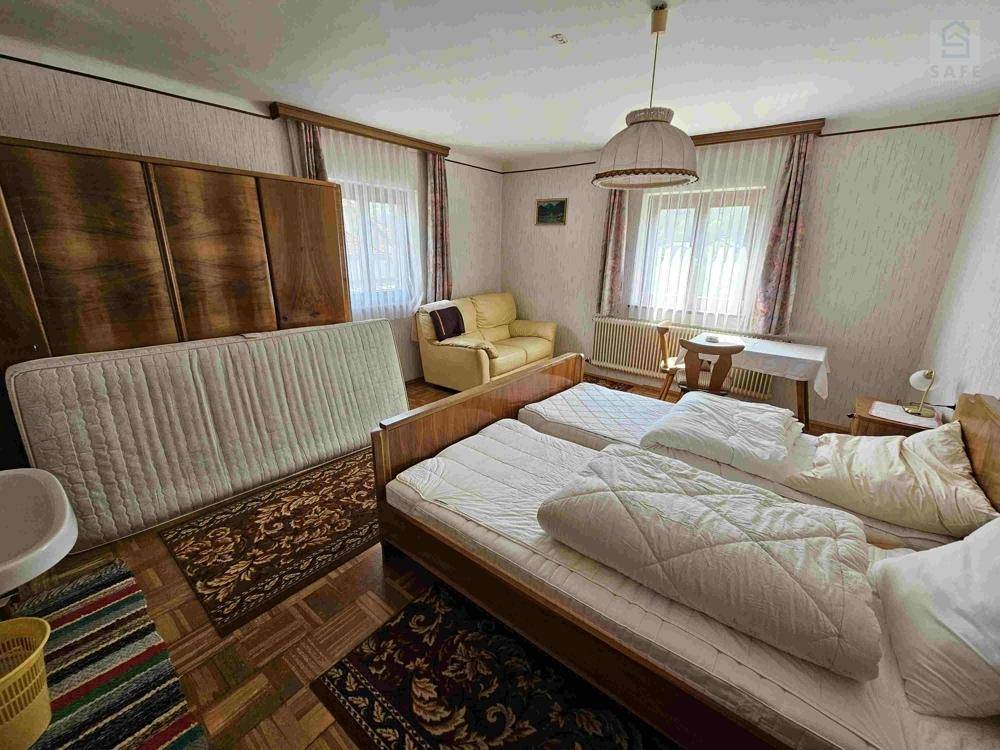 Geräumiges Schlafzimmer mit zwei Einzelbetten, Sofa und traditionellen Holzmöbeln.