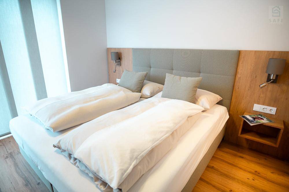 Schlafzimmer mit großem Doppelbett, Holzboden und schlichtem Design für eine ruhige Atmosphäre.