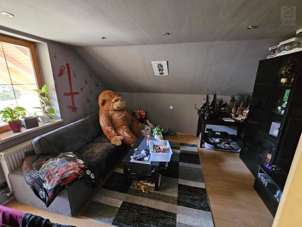 Gemütlicher Wohnbereich im Dachgeschoss mit Sofa, Teppich und schrägen Wänden.