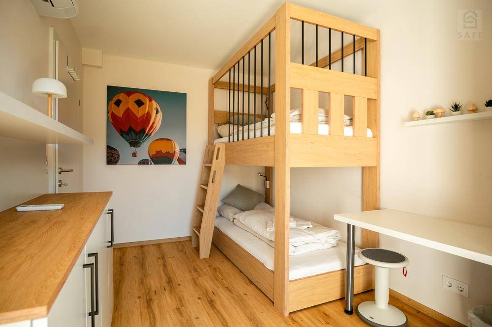 Kinderzimmer mit Etagenbett aus Holz, Schreibtisch und hellem Holzboden, ideal für Gäste oder Kinder.