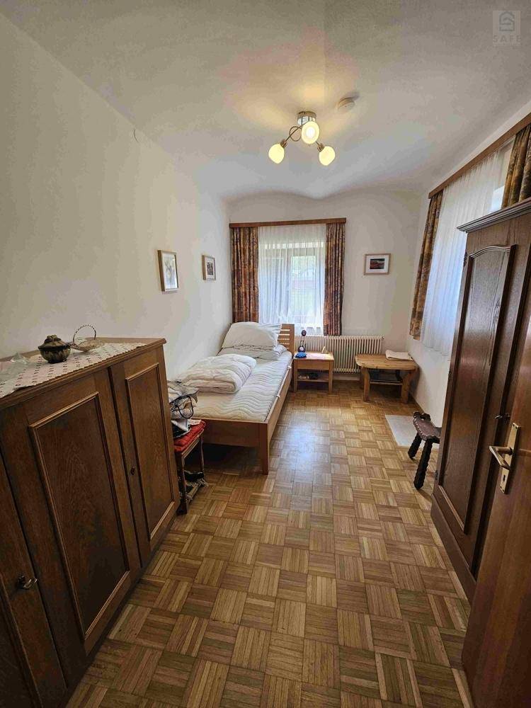 Kleines Schlafzimmer mit Einzelbett, Holzmöbeln und Parkettboden in traditionellem Stil.