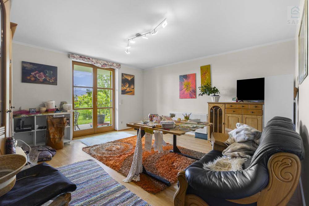 Helles Wohnzimmer mit Holzboden, Zugang zum Garten und farbenfroher Dekoration.