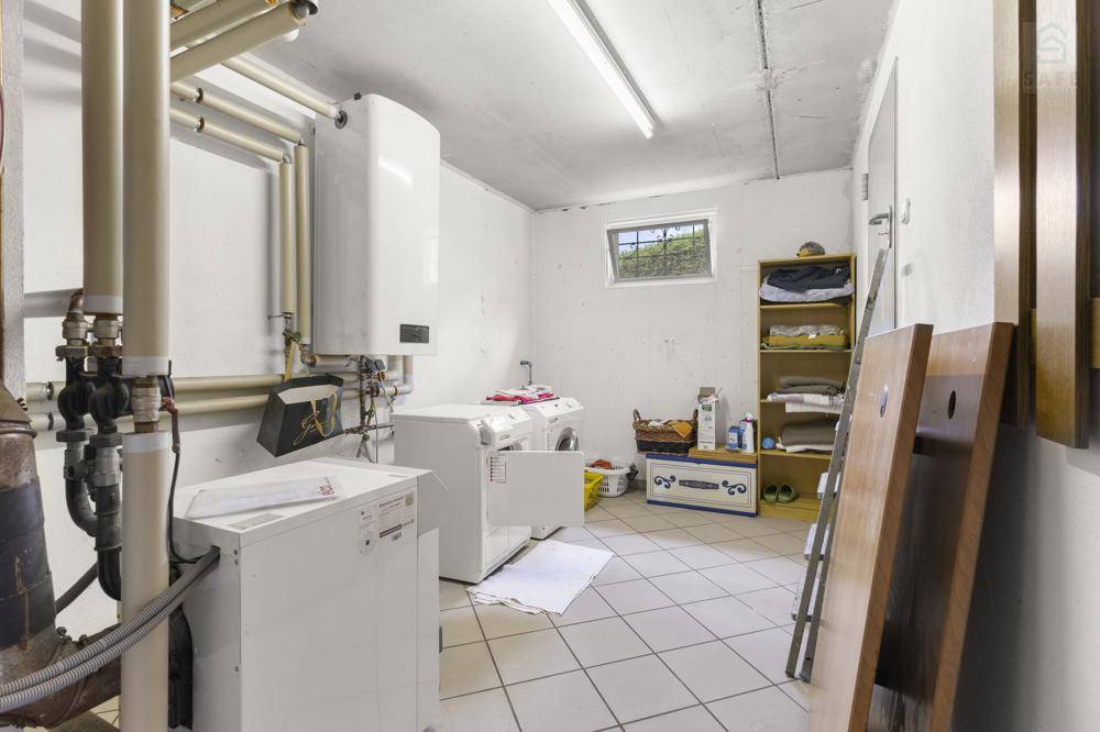 Praktischer Hauswirtschaftsraum im Keller mit Waschmaschine, Trockner und Boiler.