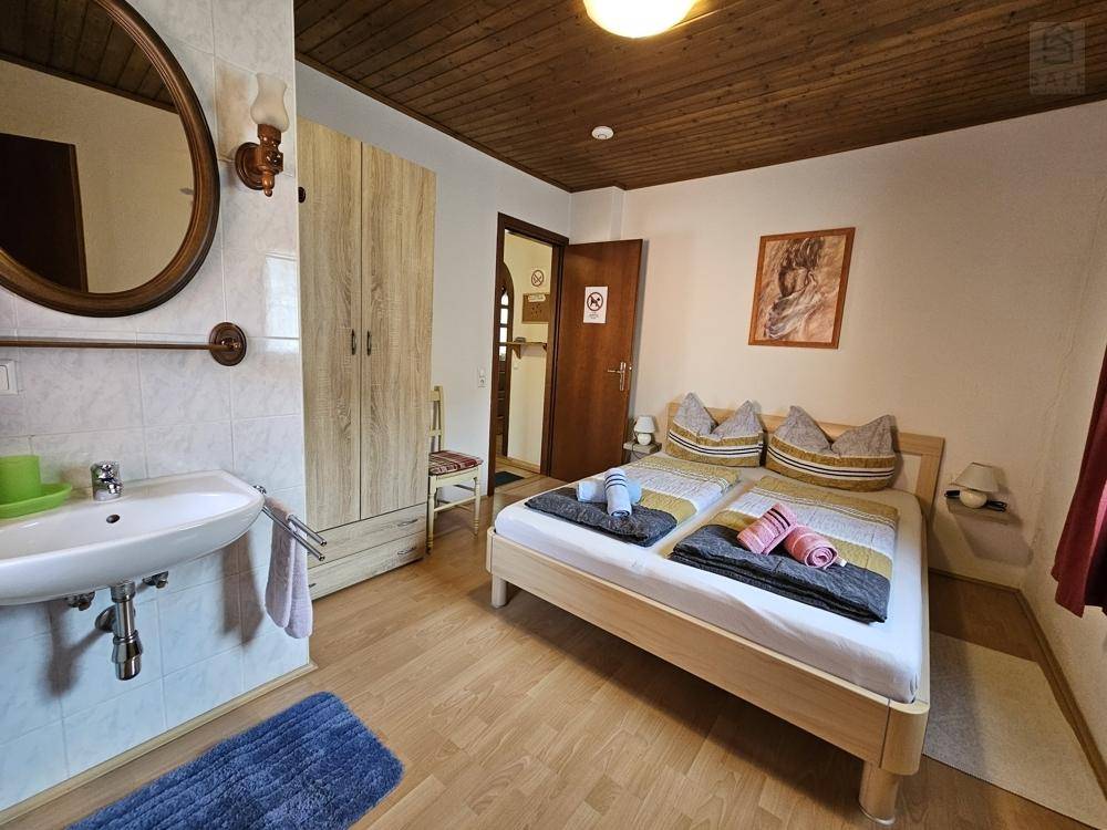 Schlafzimmer mit Doppelbett, Holzbalkendecke und integriertem Waschbecken.