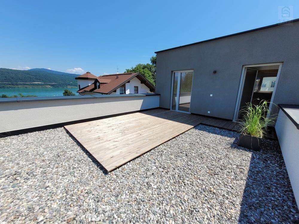 Moderne Dachterrasse mit Kies und Holzdeck, bietet einen weiten Blick auf den See.