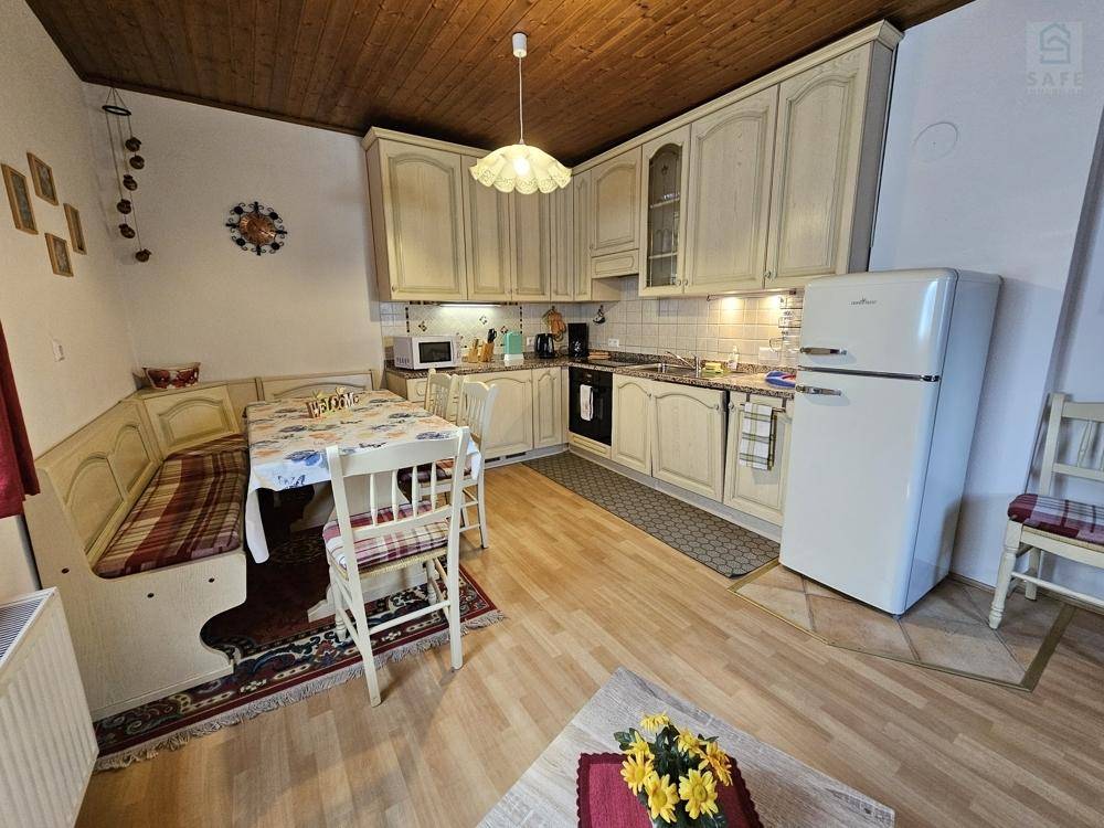 Traditionelle Küche mit hellen Holzschränken, Essbereich und Retro-Kühlschrank.