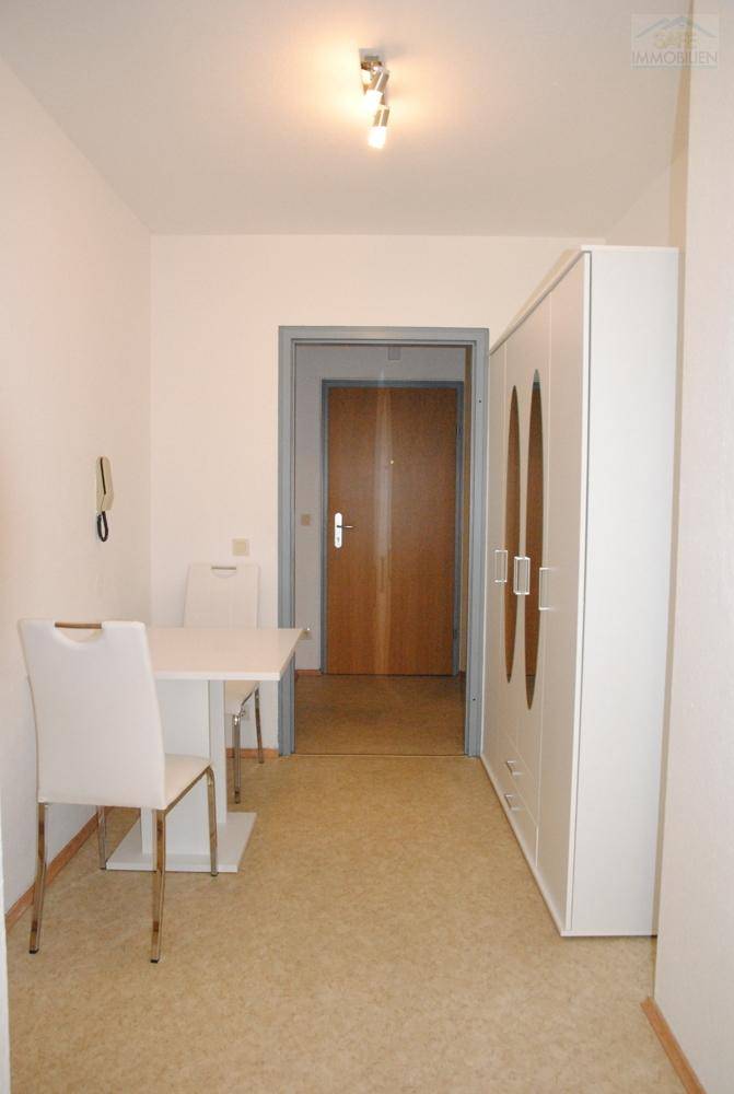 Essbereich mit modernem Tisch und Stühlen sowie einem weißen Kleiderschrank.