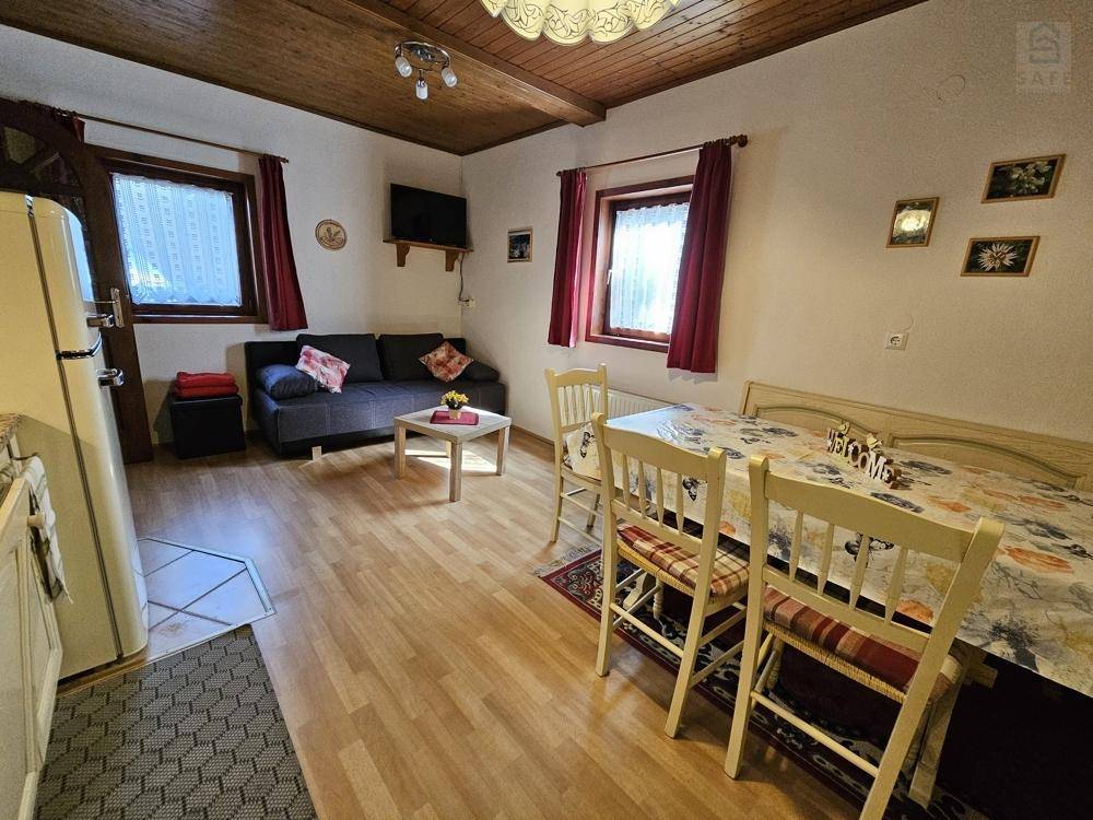 Rustikaler Wohn- und Essbereich mit Holzbalkendecke, Sofa und Esstisch.