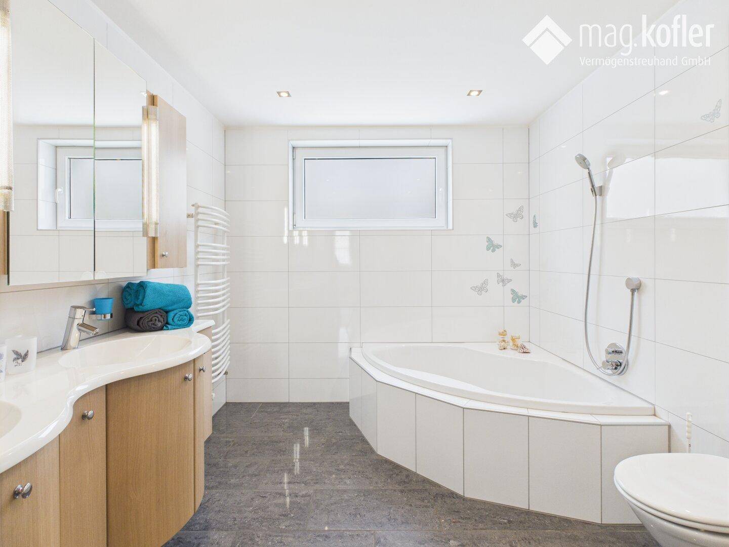 Helles modernes Badezimmer mit Eckbadewanne, Doppelwaschbecken und Fenster.