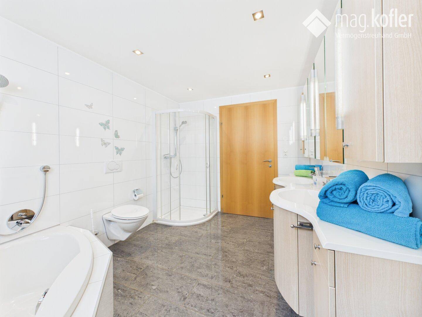 Modernes Badezimmer mit Eckbadewanne, Duschkabine und Doppelwaschbecken.
