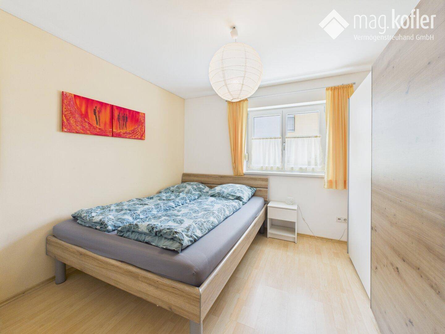 Schlafzimmer mit Doppelbett, hellem Holzboden und schlichtem Design.