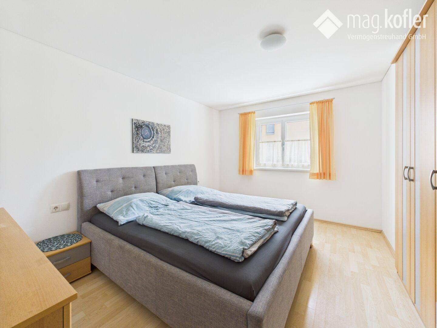 Schlafzimmer mit Doppelbett, hellem Holzboden und Einbauschränken.
