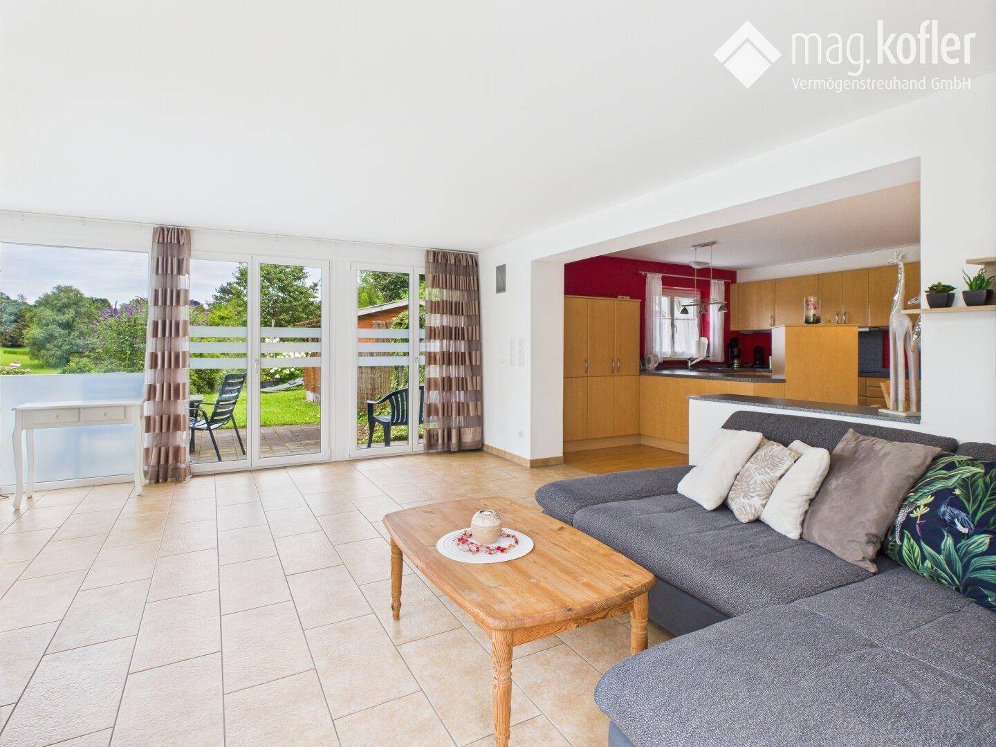 Helles Wohnzimmer mit Fliesenboden, Sofa und direktem Zugang zum Garten.