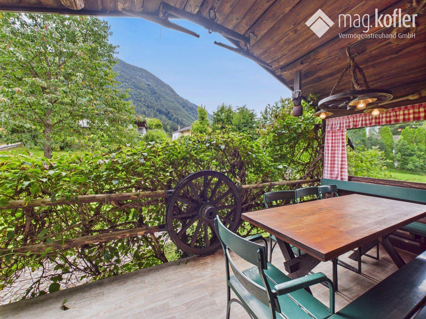 Überdachter Außenbereich mit Holztisch und Bergblick, ideal für gesellige Stunden.