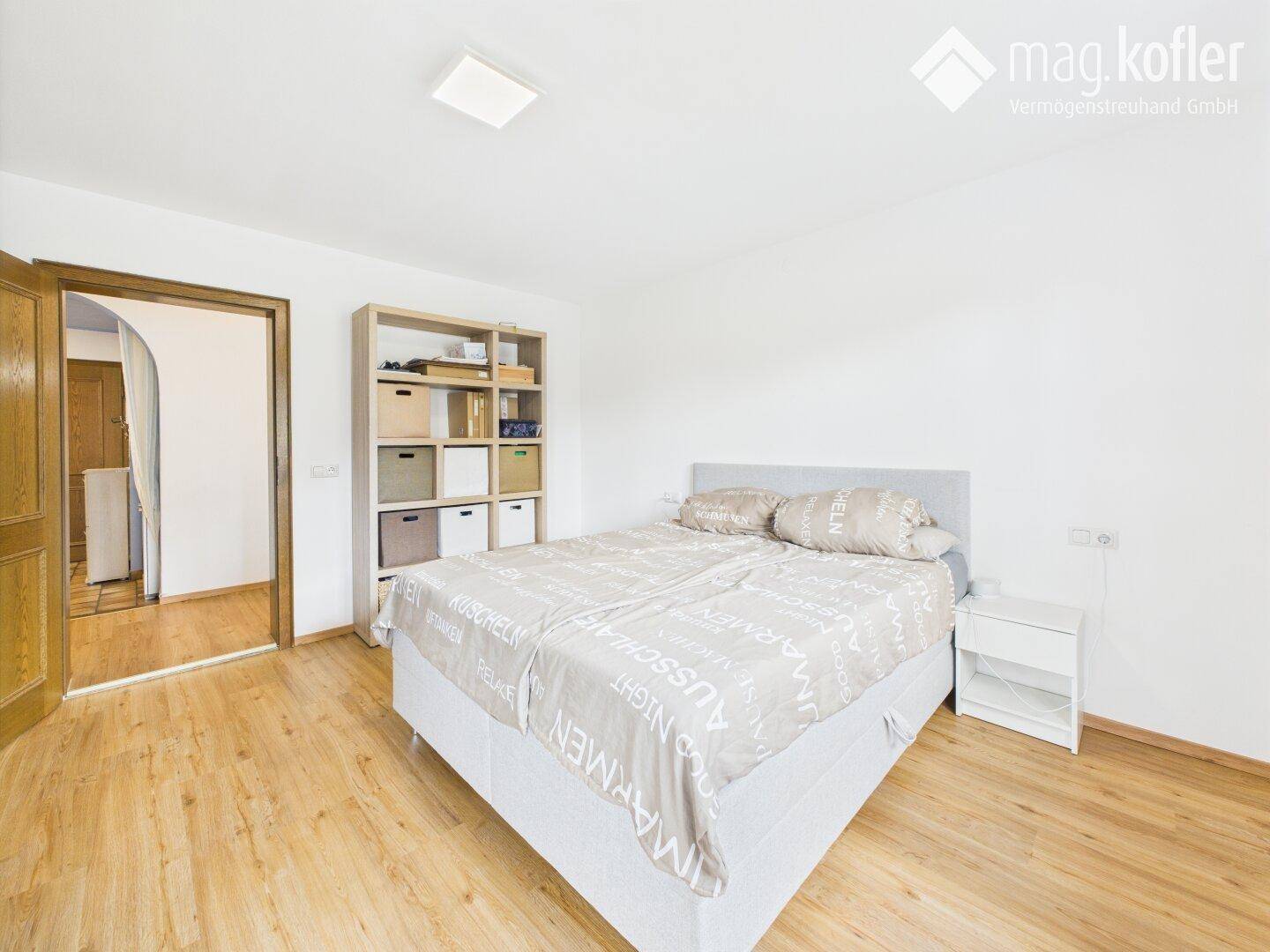 Schlafzimmer mit Doppelbett, hellem Holzboden und weiß gestrichenen Wänden.