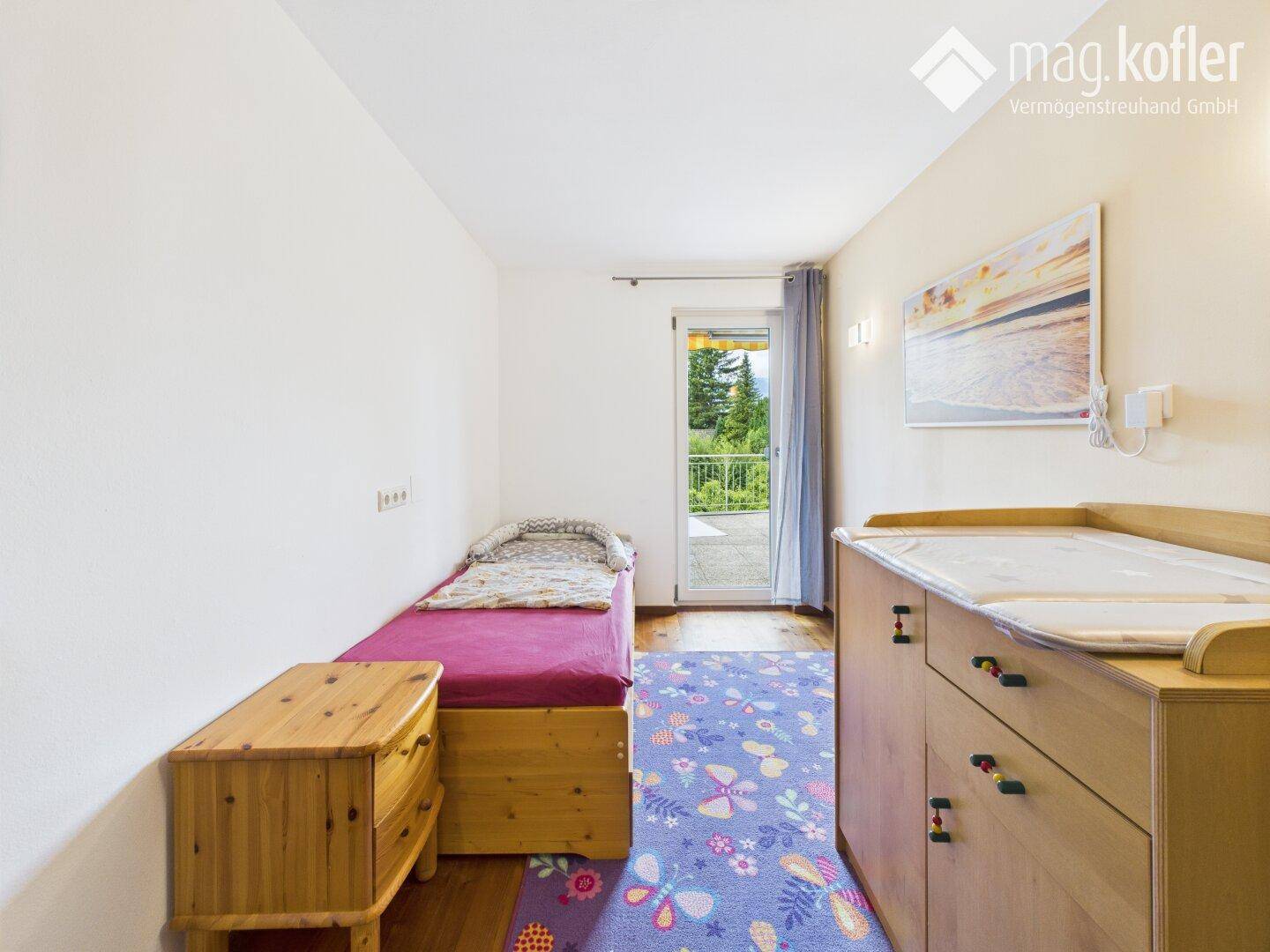 Kinderzimmer oder Gästezimmer mit Einzelbett, Wickelkommode und Zugang zum Balkon.