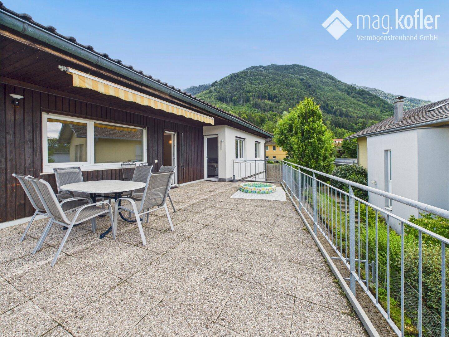 Geräumige Terrasse mit Sitzgelegenheiten und Blick auf die umliegende grüne Hügellandschaft.