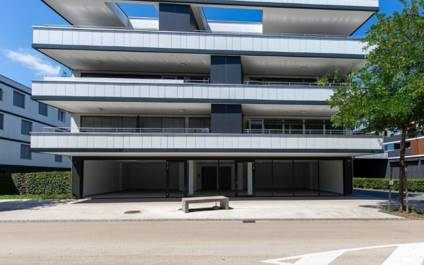 Nahaufnahme der modernen Gebäudefassade mit großen Fenstern und Balkonen im Erdgeschoss.