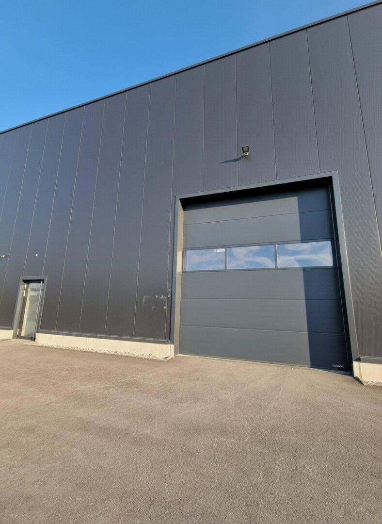 Nahaufnahme des großen Rolltors und der modernen Fassade einer neuen Gewerbeimmobilie.