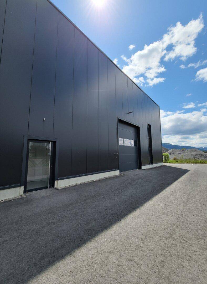 Detailansicht der modernen Gewerbefassade mit großem Rolltor und Eingangstür bei Sonnenschein.
