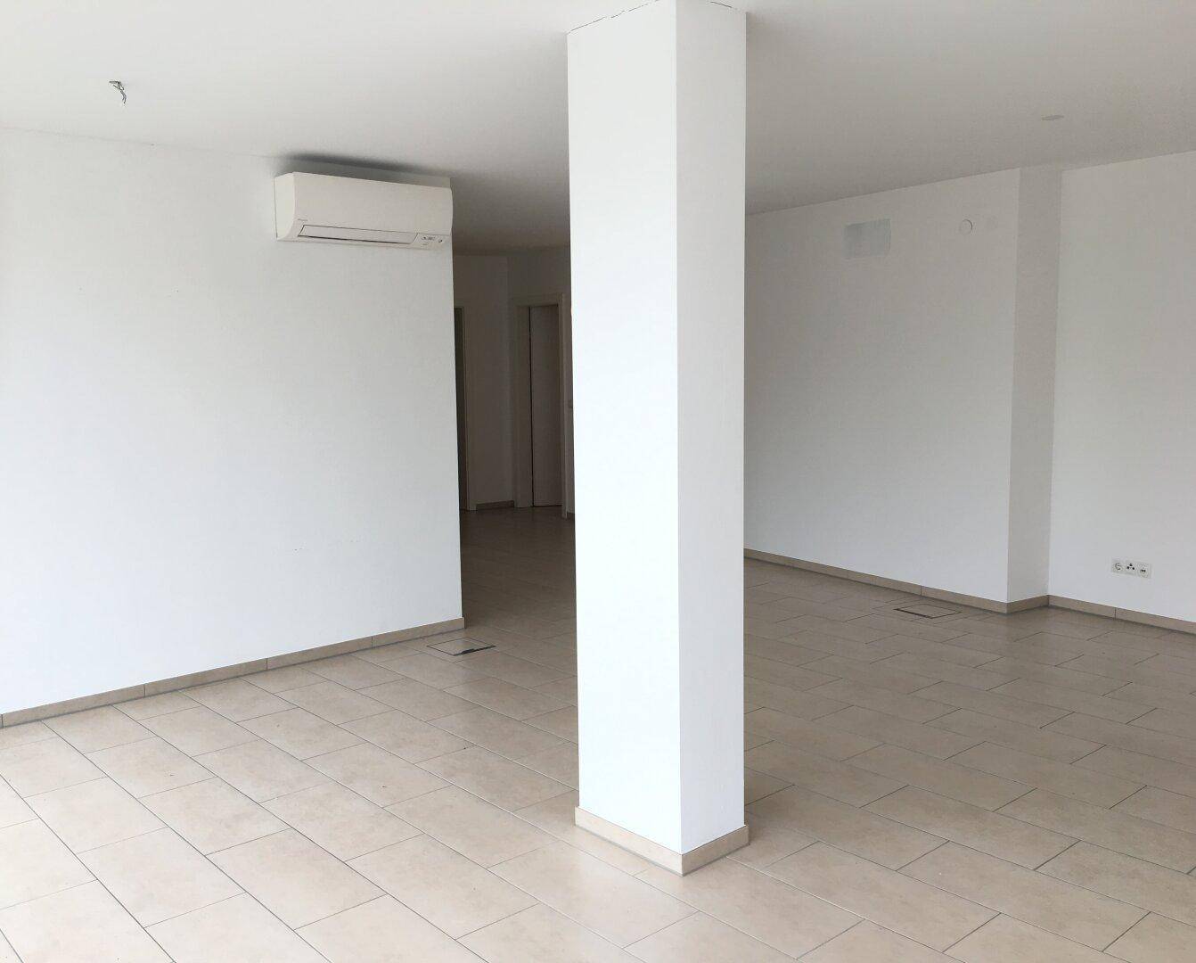 Heller, leerer Raum mit einer weißen Säule und einer Klimaanlage an der Wand.