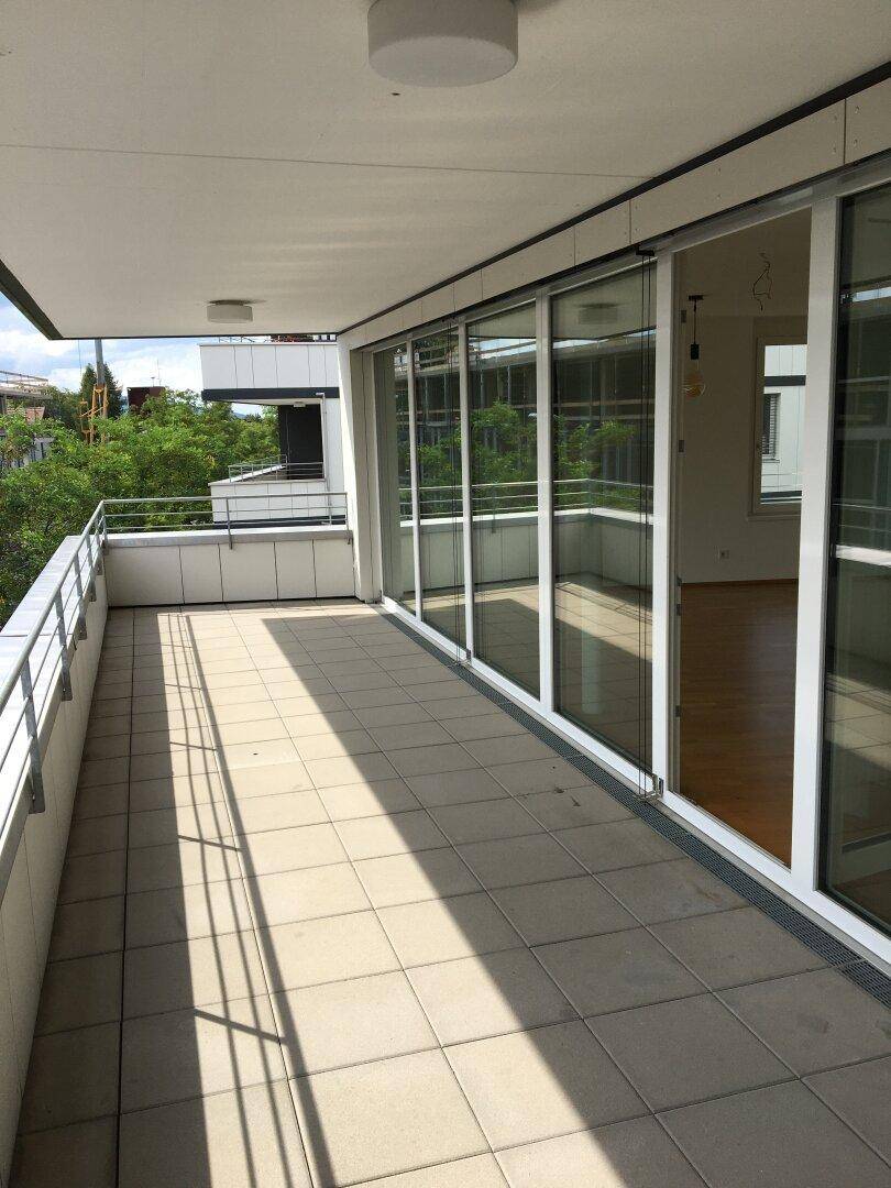 Großer, gefliester Balkon mit Metallgeländer und Blick auf die Umgebung.