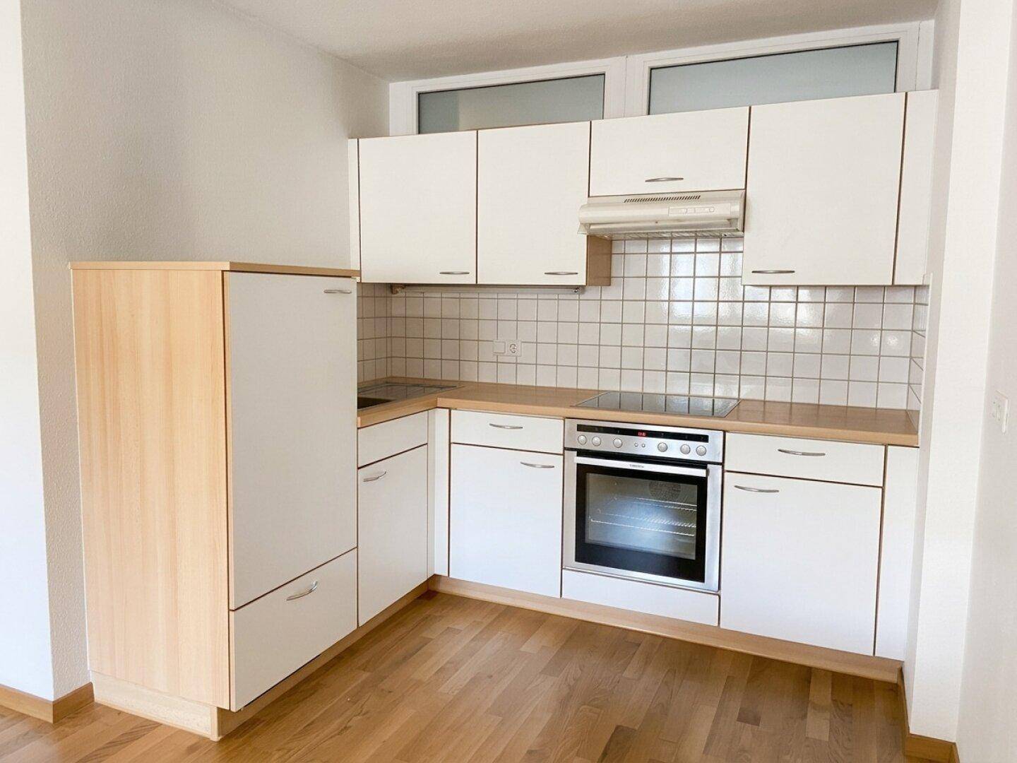 Helle Einbauküche mit weißen Schränken, Holz-Arbeitsplatte und integrierten Geräten.