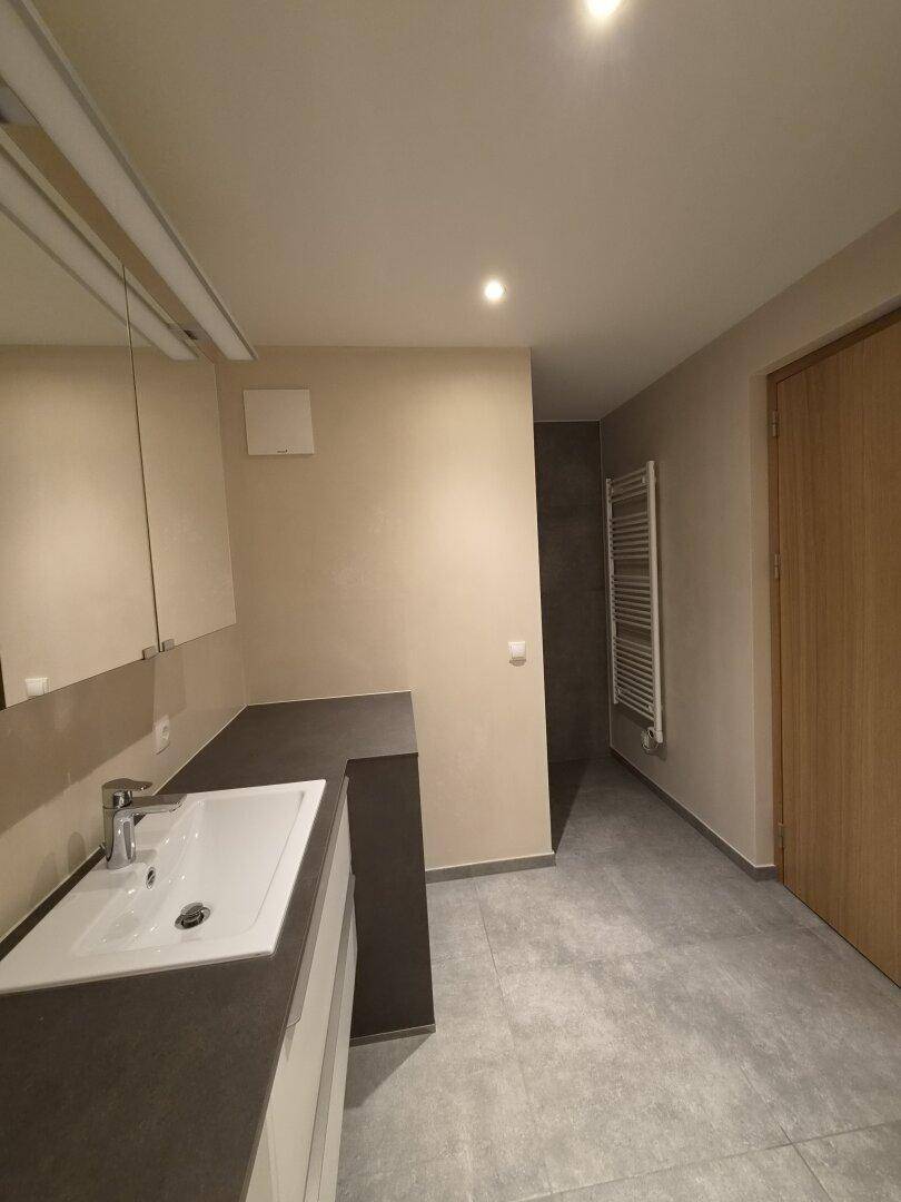 Zeitgemäßes Badezimmer mit Einzelwaschbecken, beheiztem Handtuchhalter und Duschbereich.