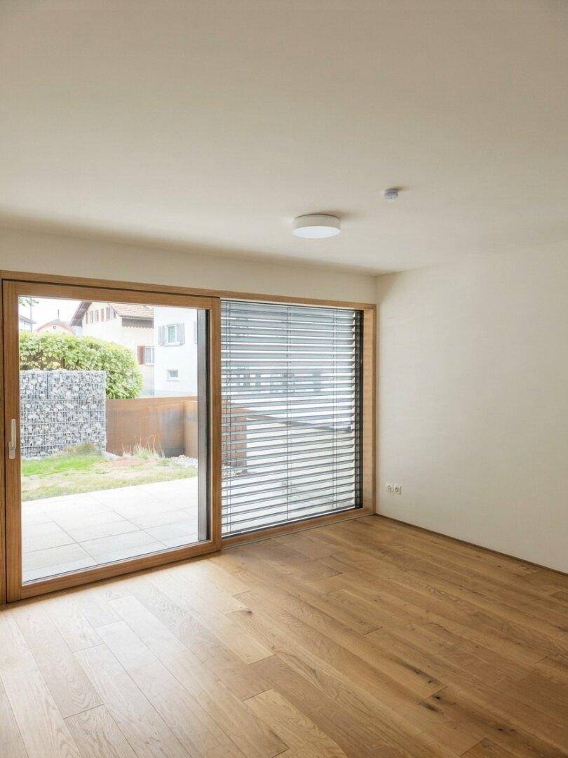 Heller Raum mit Holzboden und großer Schiebetür zum Außenbereich, bietet viel Tageslicht.