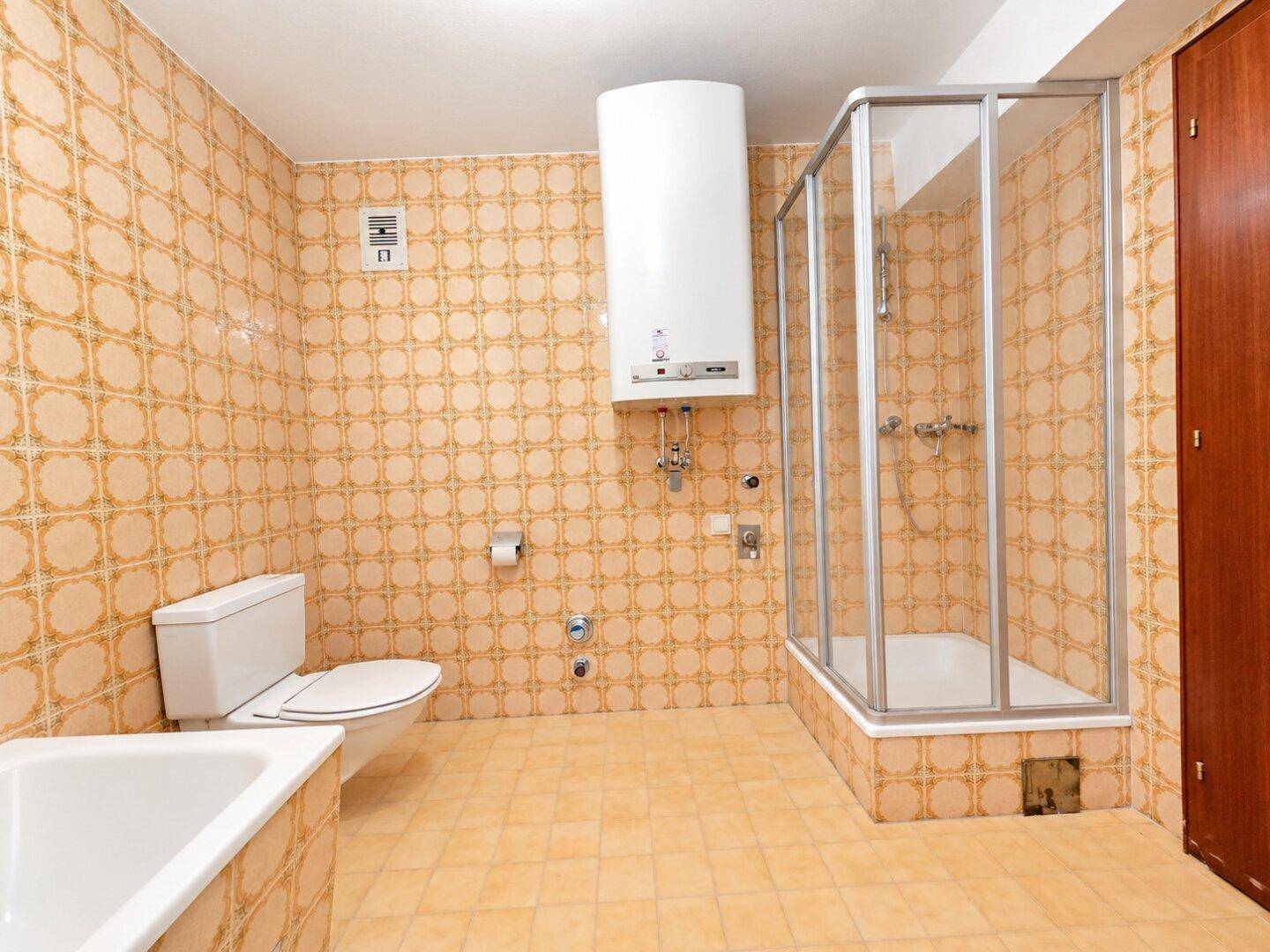 Badezimmer mit Toilette, Duschkabine und gemusterten Fliesen im Retro-Stil.