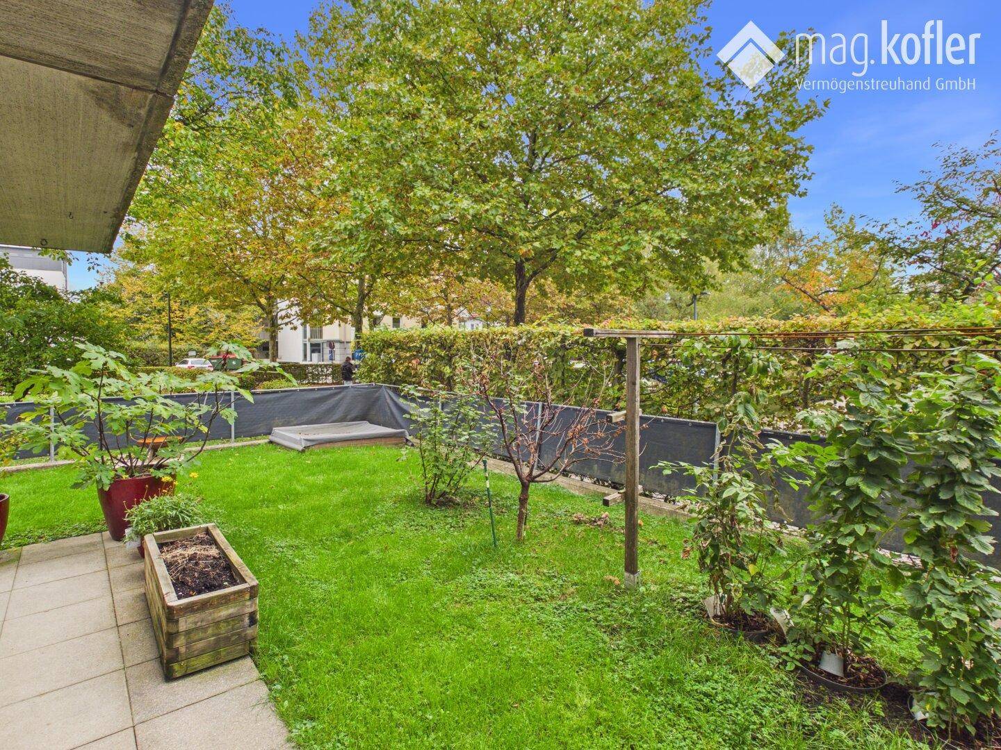 Privater Gartenbereich mit Rasen, Sträuchern und kleinen Bäumen.