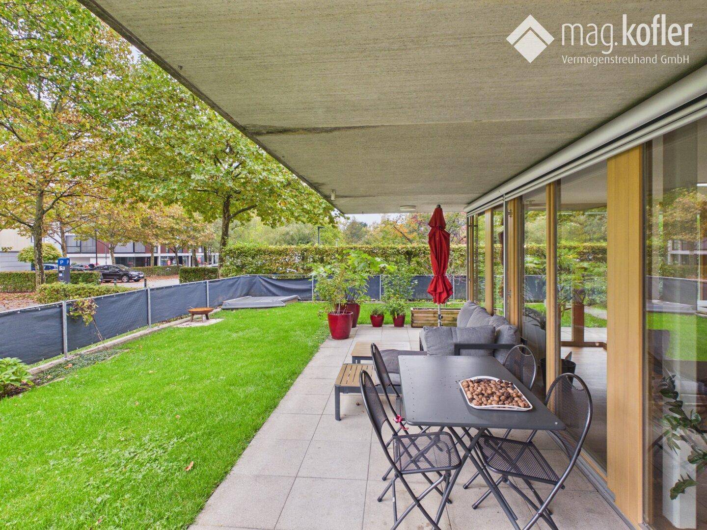 Große Terrasse mit Gartenmöbeln und angrenzender Rasenfläche im Grünen.