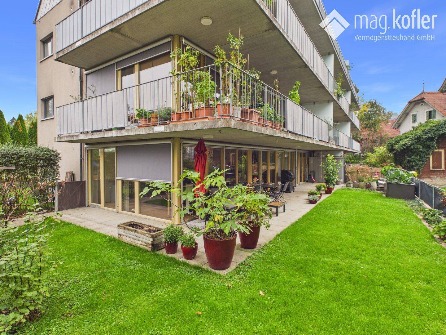Mehrfamilienhaus mit Balkonen, Terrassen und gepflegtem Gartenbereich.
