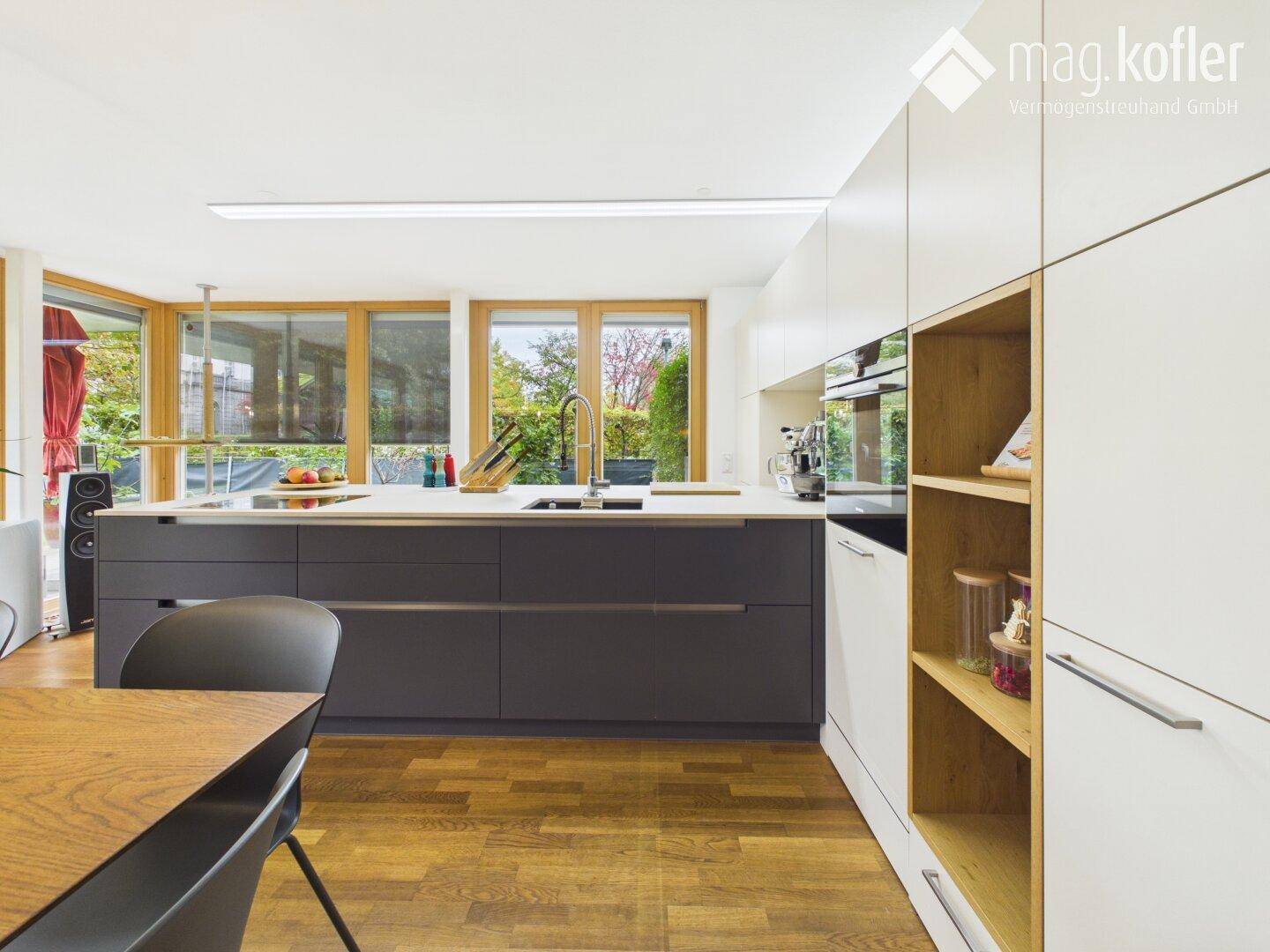 Stilvolle Küche mit integrierten Geräten, Holzdetails und Zugang zum Außenbereich.