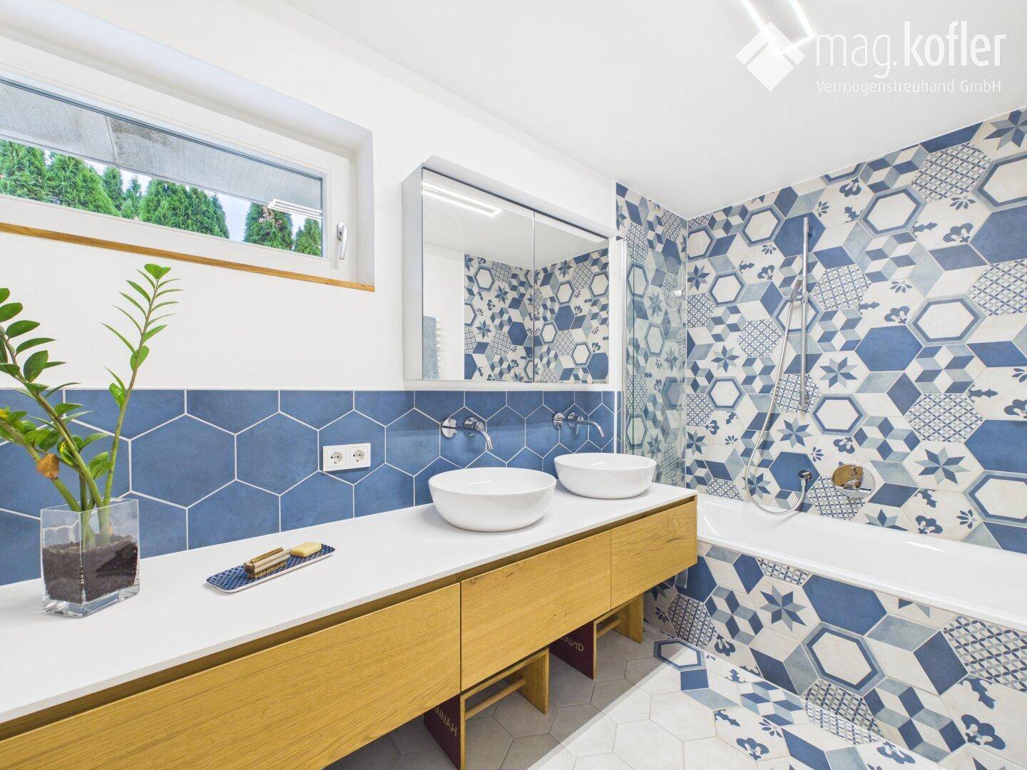 Modernes Badezimmer mit Doppelwaschbecken, Badewanne und blauen Fliesen.