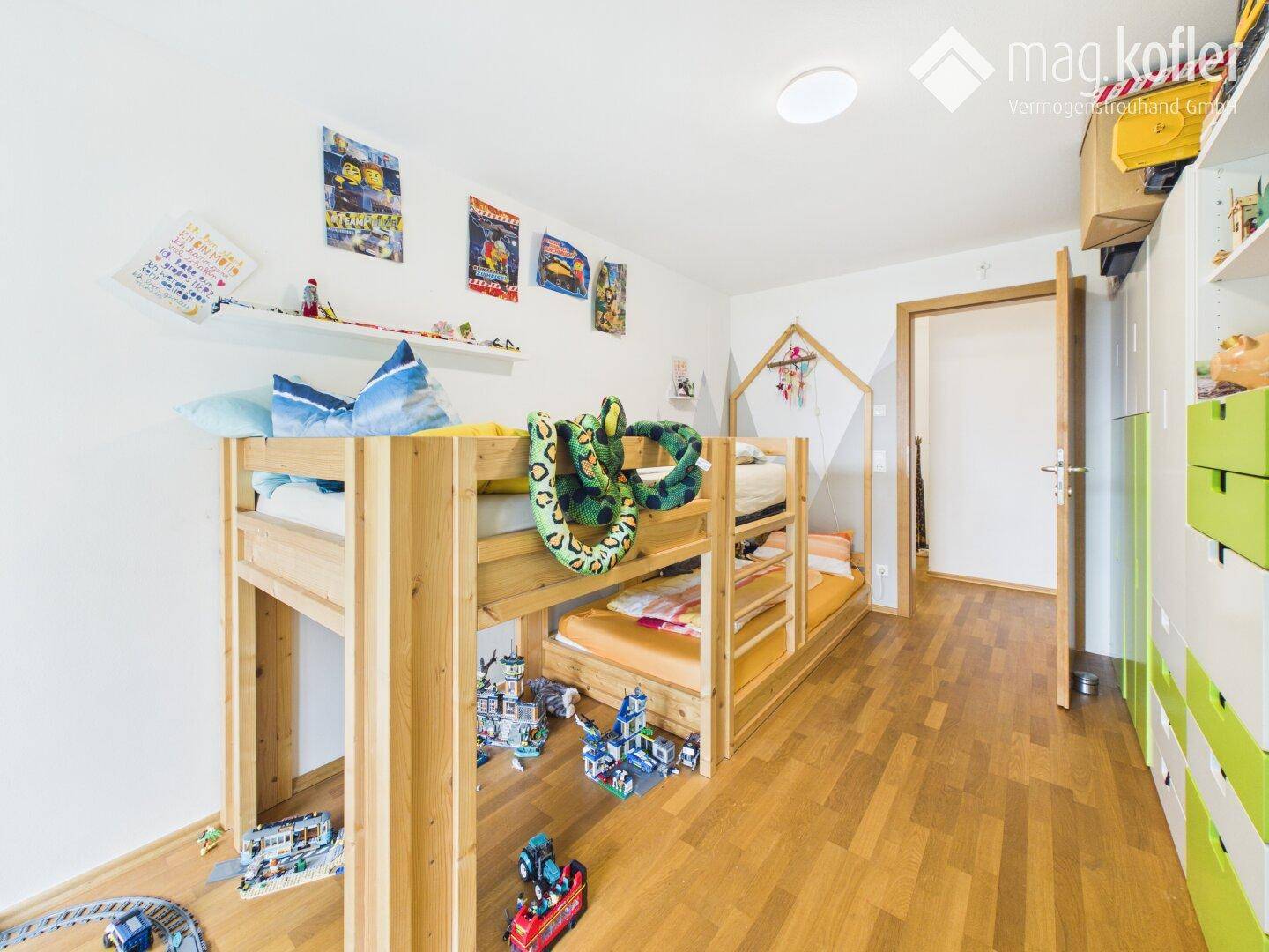 Kinderzimmer mit Etagenbett, Holzboden und bunten Dekorationen.