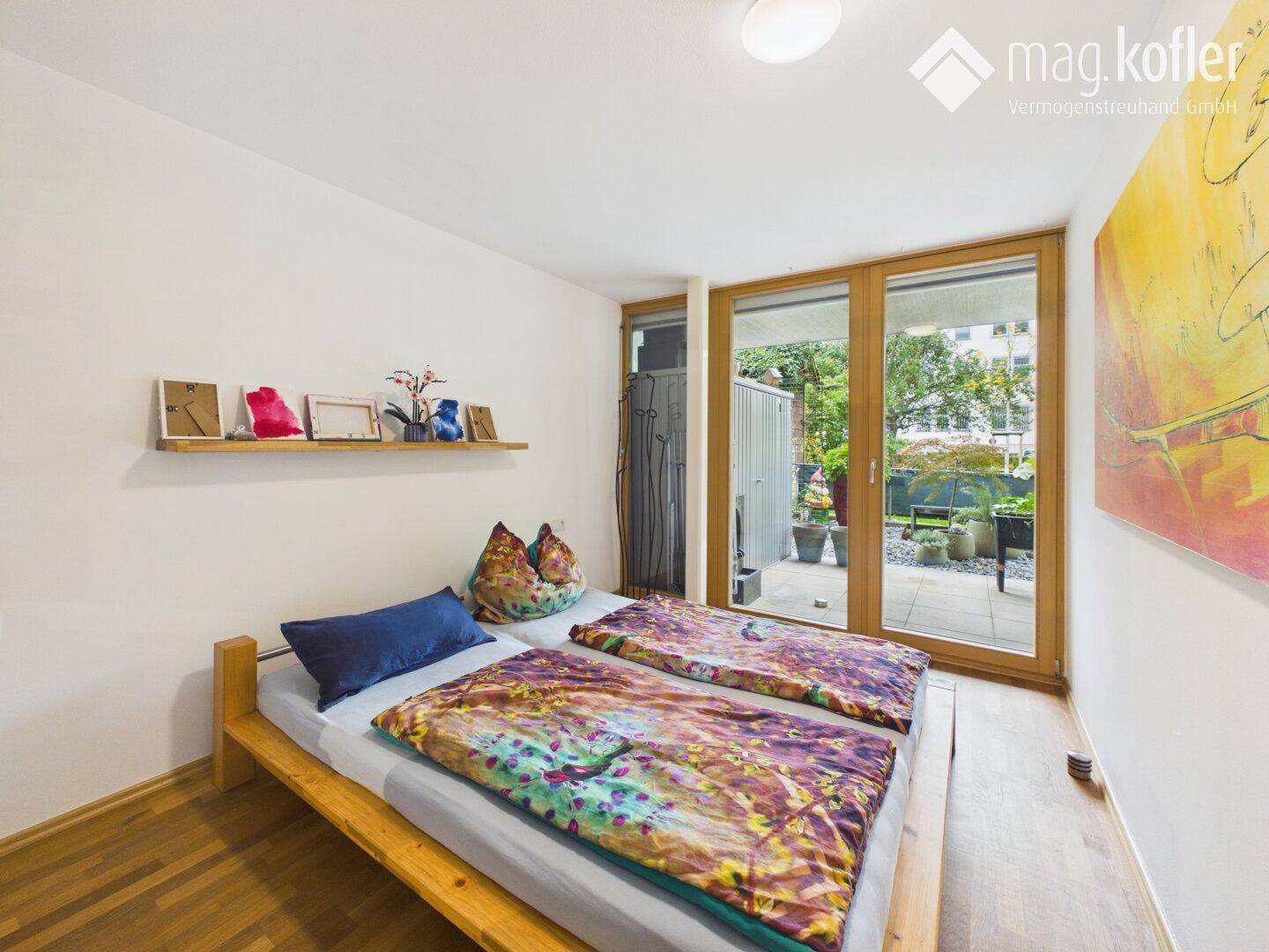 Helles Schlafzimmer mit Holzbett, Wandregal und direktem Zugang zur Terrasse.