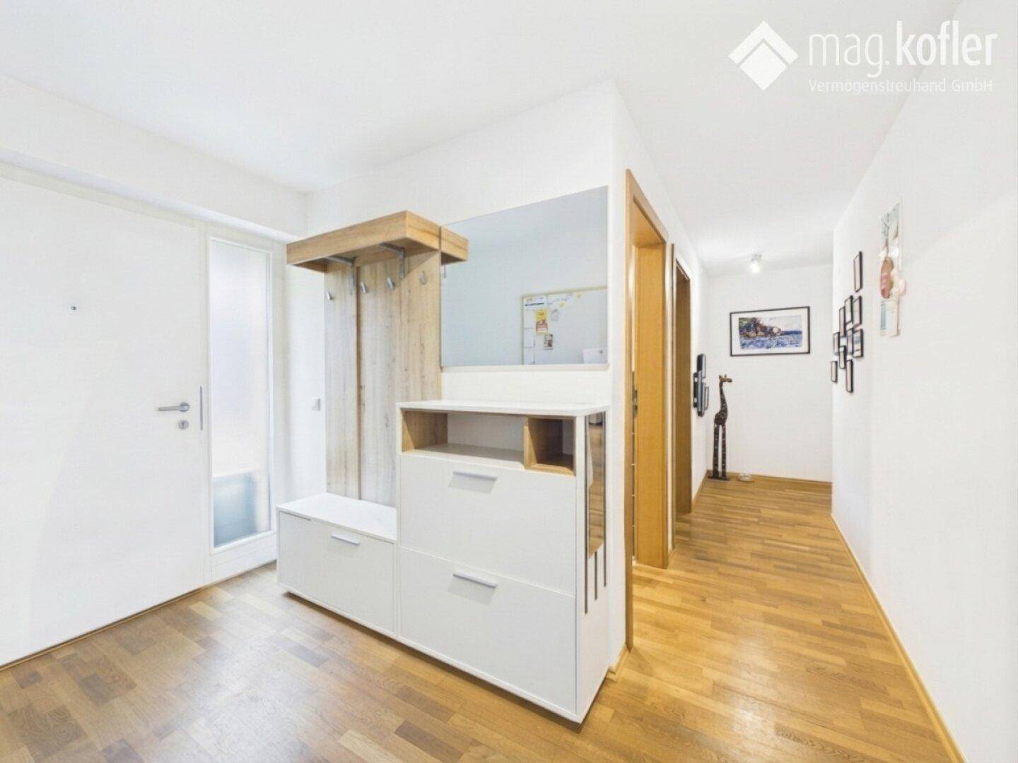 Eingangsbereich mit Garderobe, Spiegel und Holzboden.