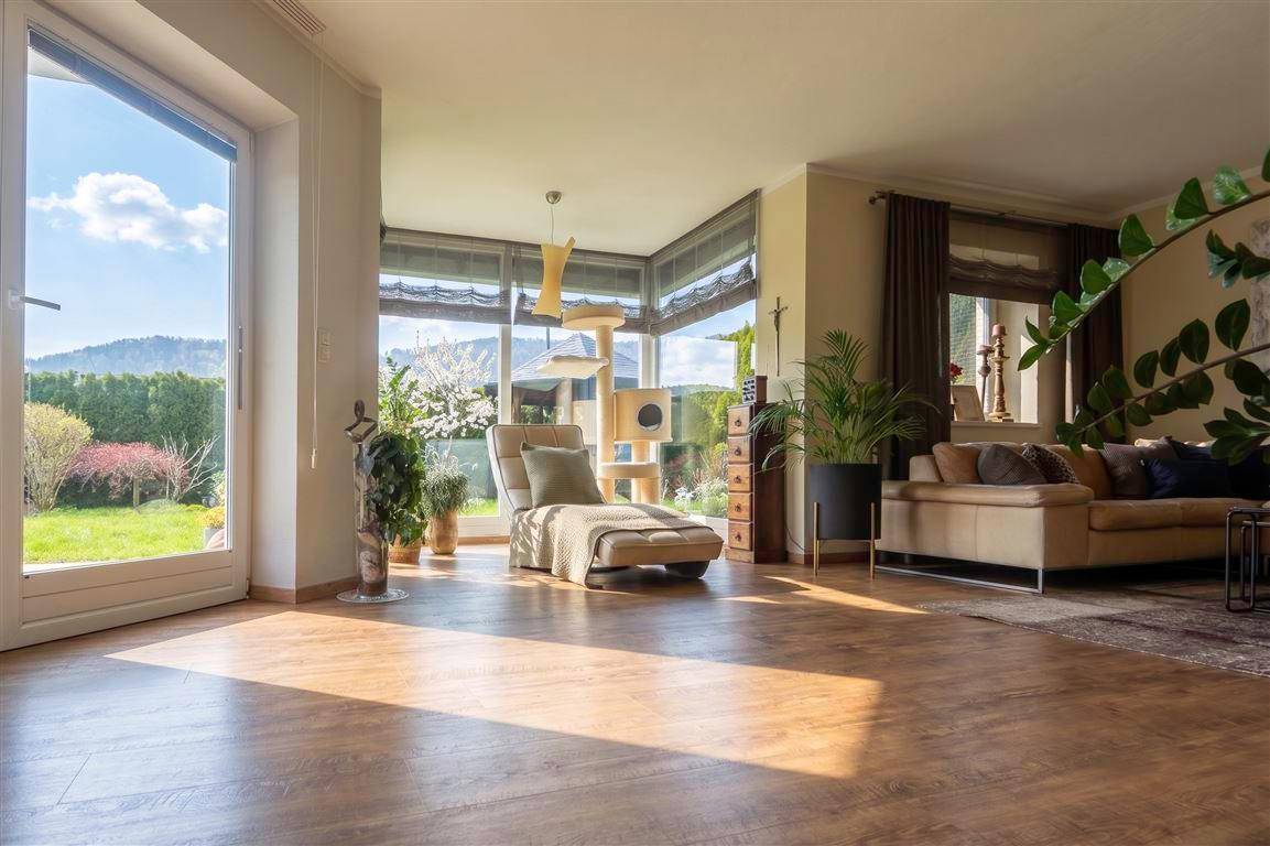 Helles Wohnzimmer mit großen Fenstern, Holzboden und Bergblick.