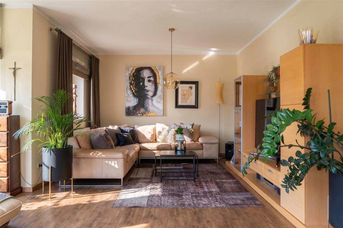 Gemütliches Wohnzimmer mit Ecksofa, Teppich und modernen Kunstwerken.