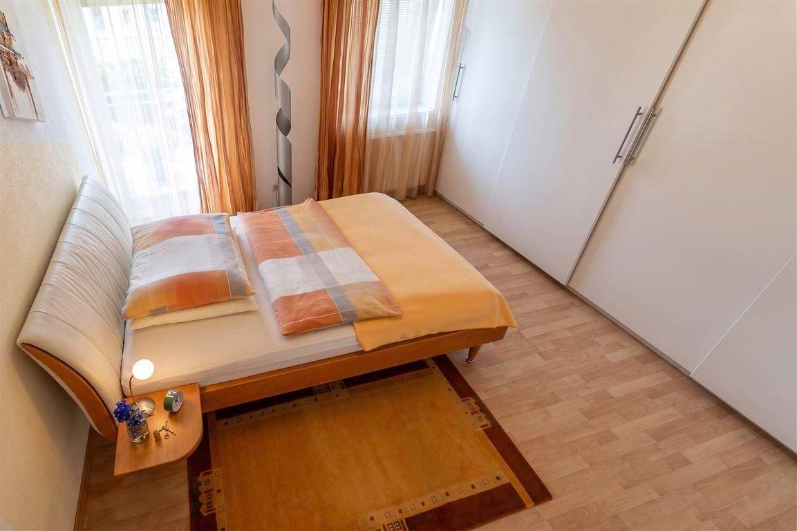 Schlafzimmer mit Doppelbett, weißen Einbauschränken und hellem Laminatboden.