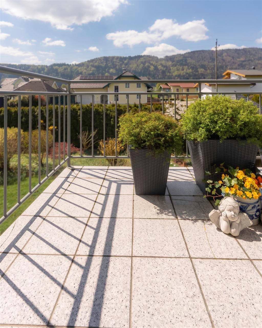 Gefliester Balkon mit Pflanzen und weitem Blick auf die Umgebung und Berge.