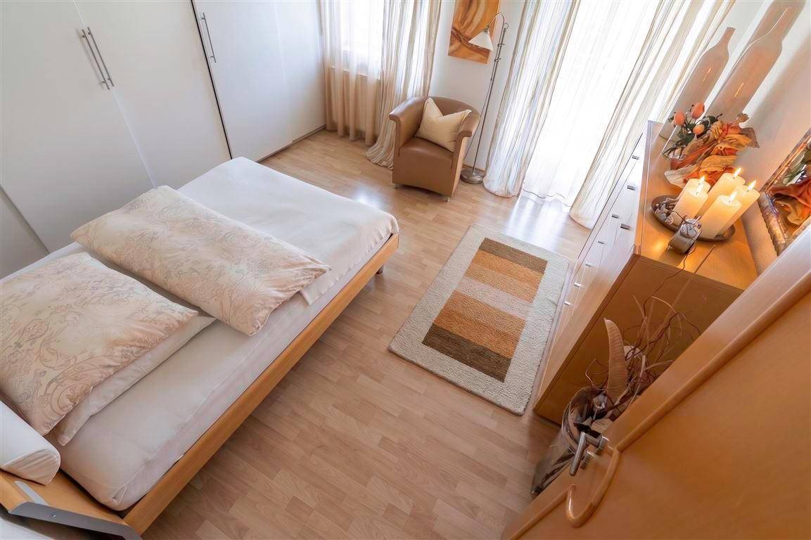 Gemütliches Schlafzimmer mit Einzelbett, Sessel und Kommode.